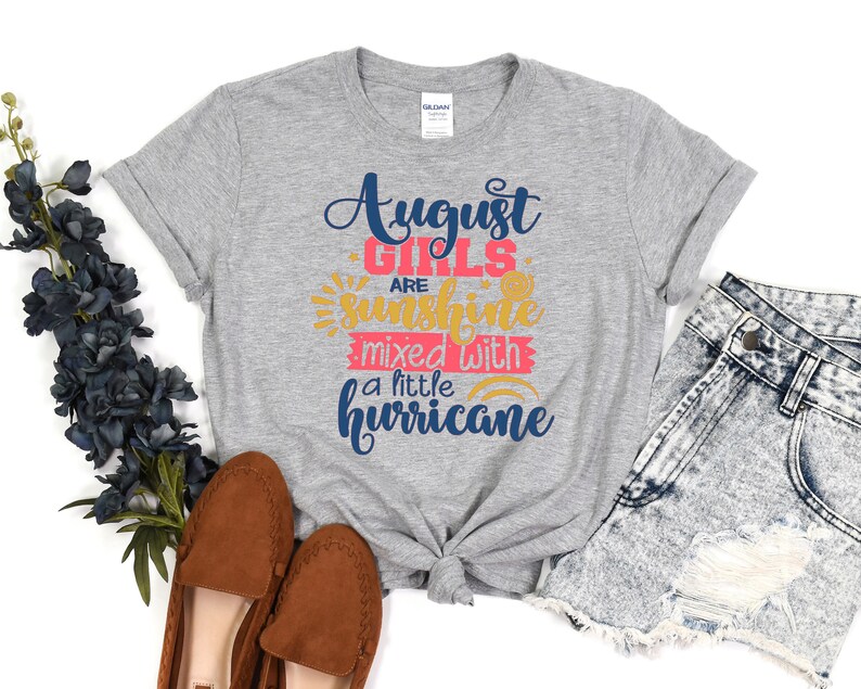 May include: Gray t-shirt with the text "August Girls are sunshine mixed with a little hurricane" in blue, pink, and yellow lettering.