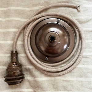 以下が含まれることがあります： ブロンズ色の金属ベースと、それに合わせた電球ソケットを備えた、ヴィンテージスタイルのシーリングライト器具。 ライト器具は、ベースの周りに巻かれたベージュの布で覆われたコードを備えています。 取り付けが簡単で、レトロな魅力を添えます。