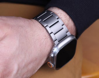 以下が含まれることがあります： シルバーのApple Watchとシルバーのメタルバンド。時計の文字盤は黒で、バンドは磨かれた仕上げです。