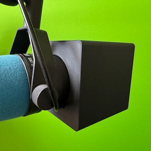 Könnte beinhalten: Ein schwarzer Schaumstoff-Popschutz, der an einem blauen Mikrofon mit einem schwarzen Metallständer befestigt ist.