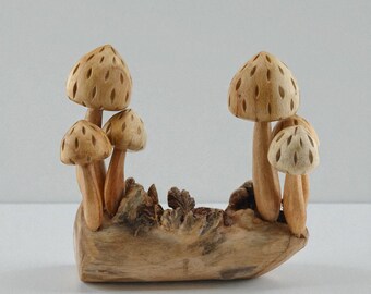 May include: A wooden sculpture featuring several carved mushrooms of varying sizes. The mushroom caps have a textured, dotted pattern. The mushrooms are attached to a natural wood base, creating a rustic, nature-inspired decorative piece.