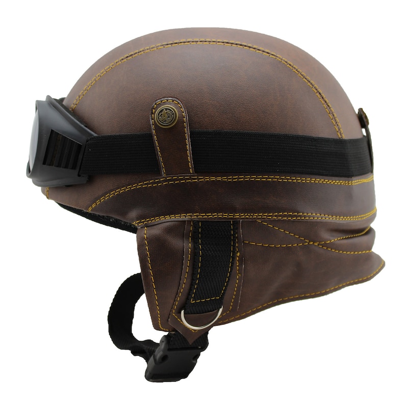 K&ouml;nnte beinhalten: Brauner Motorradhelm aus Leder mit gelben N&auml;hten und schwarzer Brille. Der Helm hat ein Vintage-Design mit schwarzem Riemen und Schnalle. Die Brille ist schwarz und mit einem schwarzen Gummiband befestigt.