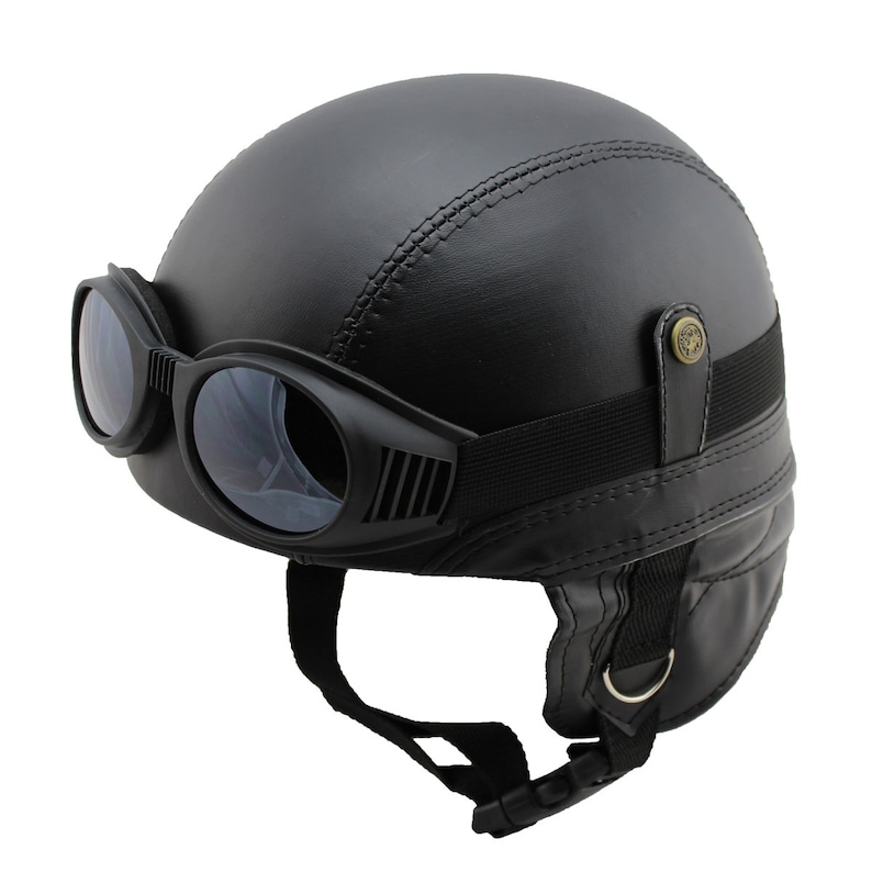 K&ouml;nnte beinhalten: Schwarzer Motorradhelm mit integrierter Brille. Der Helm hat ein gen&auml;htes Muster und einen Befestigungsriemen. Die Brille hat dunkle Gl&auml;ser und eine Vintage-&Auml;sthetik. Der Helm ist f&uuml;r Schutz und Stil konzipiert.