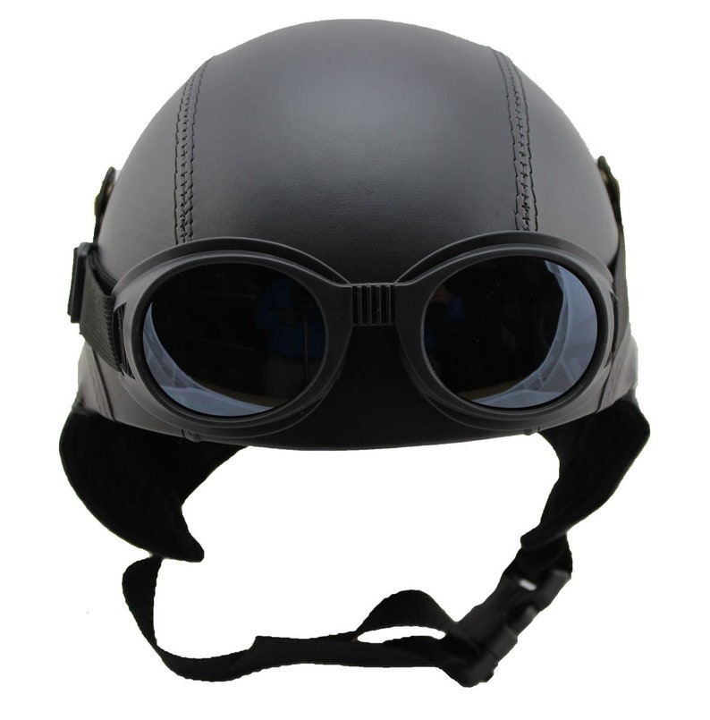 K&ouml;nnte beinhalten: Schwarzer Motorradhelm mit integrierter Brille. Der Helm hat eine runde Form mit einer Naht in der Mitte. Die Brille ist schwarz mit klaren Gl&auml;sern und einem Riemen. Er hat auch Ohrenklappen und einen Kinnriemen.
