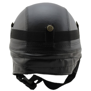 K&ouml;nnte beinhalten: Schwarzer Motorradhelm aus Leder mit Steppn&auml;hten. Er hat ein schwarzes Gummiband und einen Schnallenriemen zur Befestigung. Enth&auml;lt einen dekorativen Messingknopf auf der R&uuml;ckseite.