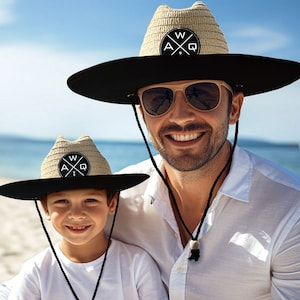 May include: Two straw hats with black brims and chin straps. Each hat has a circular patch with the letters "A", "W", and "Q" arranged around a cross. One hat is on an adult, the other on a child.