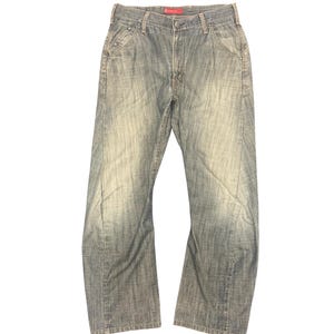 May include: A white ceramic mug with a black handle and the text "But First, Coffee" in a bold, black font. The mug is set against a blurred background, suggesting a cosy setting.