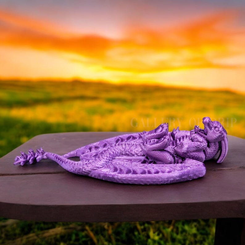 May include: A purple 3D printed dragon figurine curled up in a sleeping position. The dragon has detailed scales and wings.