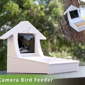 May include: White bird feeder with a built-in camera, designed to house a Blink camera. The feeder has a birdhouse shape with a small bird silhouette on the roof. The text "Blink Camera Bird Feeder" is at the bottom.