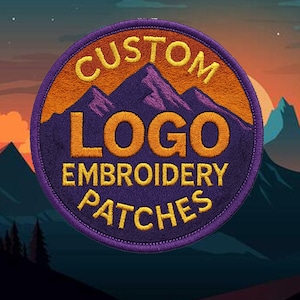 May include: Circular embroidered patch with a purple border. The patch features a mountain scene and the words "CUSTOM LOGO EMBROIDERY PATCHES" in yellow and orange thread. The background shows a sunset.