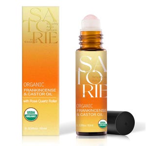 May include: An organic frankincense and castor oil roller bottle with a rose quartz roller. The bottle is amber-colored with a black cap and a label that reads "SATORIE" and "USDA ORGANIC". The product is 0.33 fl oz, 10 ml.