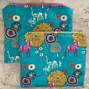 May include: Two turquoise zippered pouches with a colorful floral and animal print design. The pouches are stacked on top of each other.