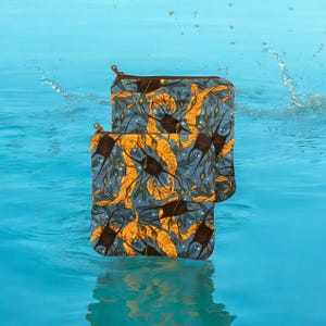 May include: Two zippered pouches with a marine-themed pattern. The design features stylized yellow and brown manta rays and seaweed on a blue background. The pouches are floating in blue water.