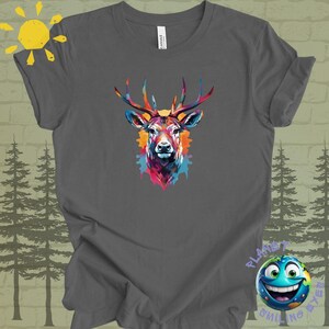 Puede incluir: Una camiseta gris oscuro con un diseño abstracto de cabeza de ciervo colorido. El ciervo tiene grandes cuernos y un efecto de acuarela.