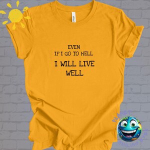 以下が含まれることがあります： 黒い文字で「Even if I go to hell I will live well」とプリントされた黄色のTシャツ