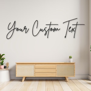 Puede incluir: Texto negro en cursiva sobre una pared blanca que dice "Your Custom Text". Debajo, un mueble de madera clara con paneles tejidos y tres cajones se asienta sobre un suelo de madera clara. Se ve un pequeño cactus en maceta y otra decoración.