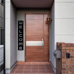 Pu&ograve; includere: Una porta d'ingresso in legno con un accento argentato orizzontale e un cartello nero con la scritta "WELCOME". La porta &egrave; inserita in un ingresso incassato con un esterno in mattoni e pietra. Una lanterna in stile vintage &egrave; montata sopra la porta.