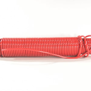 May include: A coiled red hose with a silver fitting on each end. The hose is tightly wound, with a smooth, glossy finish. A length of the hose extends from the coil. The background is plain white.