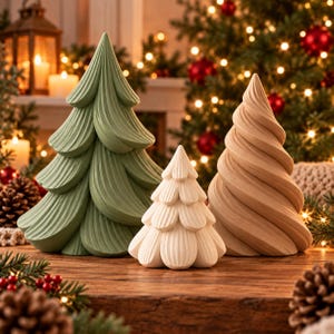 Peut inclure: Trois figurines d'arbres décoratives disposées sur une surface en bois. Le plus grand arbre est vert sauge avec des branches texturées en couches. Un arbre plus petit, couleur crème, aux couches en forme de pétales, est au centre.