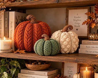 May include: Three decorative pumpkins crafted from yarn, featuring a large orange pumpkin with a braided texture, a smaller sage green pumpkin with a similar braided pattern, and a cream-colored pumpkin with a textured bobble stitch design.
