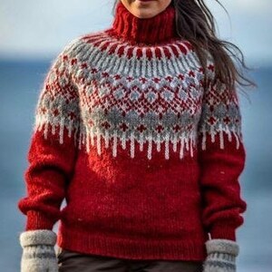 Puede incluir: Un su&eacute;ter de punto rojo, gris y blanco con un patr&oacute;n tradicional escandinavo. El su&eacute;ter tiene cuello alto y mangas largas.