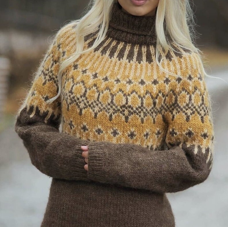 Puede incluir: Un su&eacute;ter de punto marr&oacute;n y amarillo con un patr&oacute;n geom&eacute;trico. El su&eacute;ter tiene cuello alto y mangas largas.