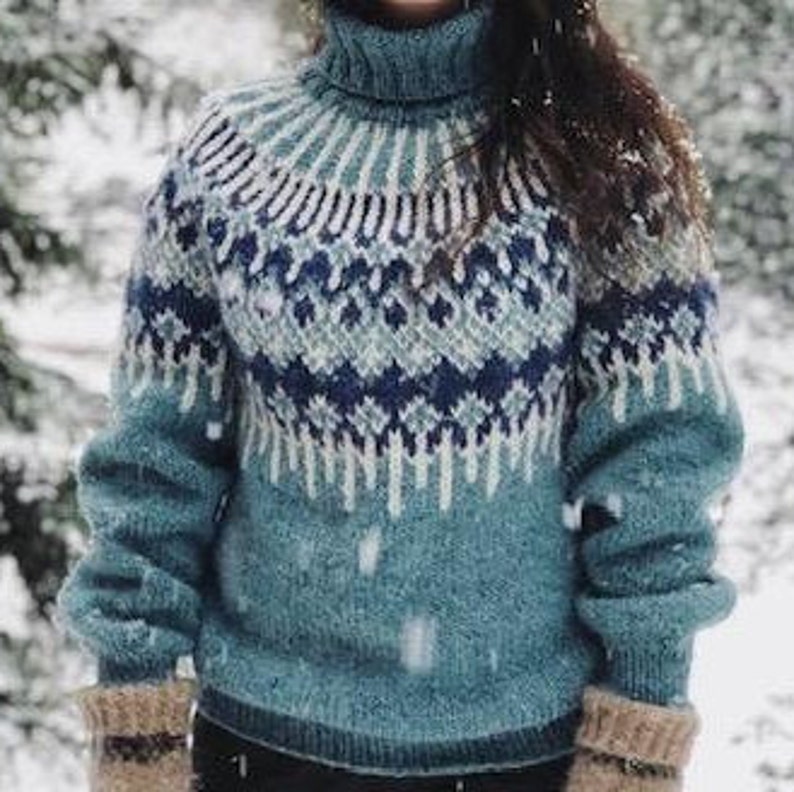 Puede incluir: Un su&eacute;ter de cuello alto azul, blanco y gris con un dise&ntilde;o de punto de trenza. El su&eacute;ter est&aacute; hecho de una tela suave y tejida.