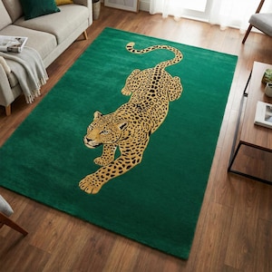 May include: A rectangular area rug featuring a deep emerald green background with a large, centred illustration of a golden leopard in a prowling position. The leopard has black spots and is oriented diagonally across the rug surface.