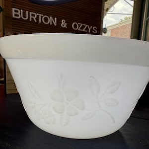 Peut inclure: Un saladier blanc avec un motif floral gravé sur le côté. Le saladier a un large bord et une forme lisse et incurvée. Le motif floral comprend des fleurs et des feuilles.