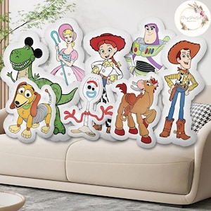 Op de afbeelding: Een set van acht pluche kussens met personages uit de Toy Story-franchise. De personages zijn Woody, Buzz Lightyear, Jessie, Rex, Slinky Dog, Bo Peep, Forky en Bullseye. De kussens zijn allemaal wit met kleurrijke cartoonafbeeldingen van de personages.