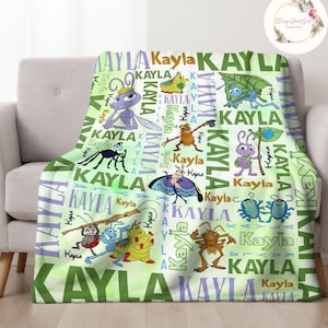 May include: A green and purple fleece blanket with a repeating pattern of the name "Kayla" and images of bugs from the movie A Bug's Life.