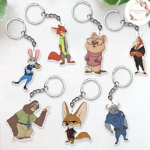 May include: A collection of character keychains featuring various animals from the animated movie Zootopia. Each keychain has a silver chain and ring. The characters include a fox, a rabbit, a sloth, a bear, a horse, a fennec fox, and a buffalo.