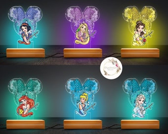 Könnte beinhalten: Sechs verschiedene Disney-Prinzessinnen-Nachtlichter. Jedes Licht zeigt eine Prinzessin in einer Mickey-Maus-förmigen Silhouette. Die Prinzessinnen sind Schneewittchen, Rapunzel, Belle, Arielle, Cinderella und Elsa. Die Lichter stehen auf Holzsockeln und haben verschiedene Farben.