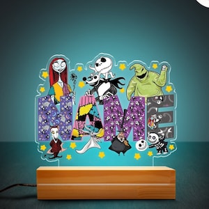 May include: A light-up name sign featuring characters from The Nightmare Before Christmas. The sign is made of clear acrylic and has a wooden base. The letters are decorated with a purple, pink, and green pattern. The characters include Jack Skellington, Sally, and Oogie Boogie.