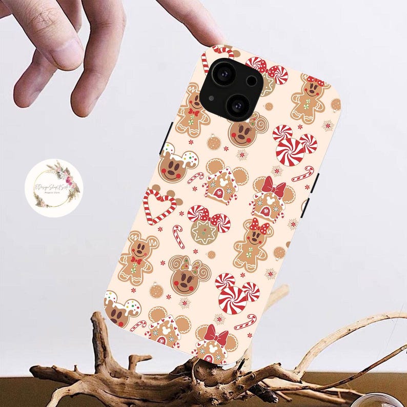 May include: A white phone case with a gingerbread cookie pattern featuring Mickey Mouse and Minnie Mouse. The case has a red and white candy cane design and a gingerbread house.