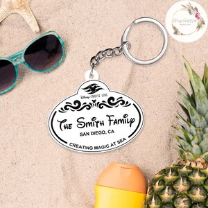 May include: White Disney Cruise Line luggage tag with black text that reads "The Smith Family, San Diego, CA, Creating Magic at Sea". The tag is attached to a silver key chain.