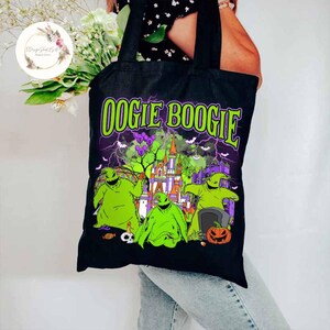 Puede incluir: Bolsa de tela negra con un gr&aacute;fico verde, morado y blanco de Oogie Boogie de Pesadilla Antes de Navidad. El gr&aacute;fico presenta a Oogie Boogie frente a un castillo con el texto "Oogie Boogie" arriba.