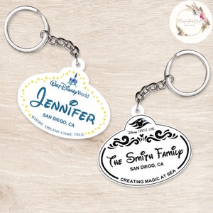 May include: Two white plastic Disney-themed name tag keychains. The first keychain says "WALT DISNEY World" and "JENNIFER" in blue text with yellow stars. The second keychain says "Disney Cruise Line" and "THE SMITH FAMILY" in black text with a black Mickey Mouse head logo. Both keychains say "SAN DIEGO, CA".