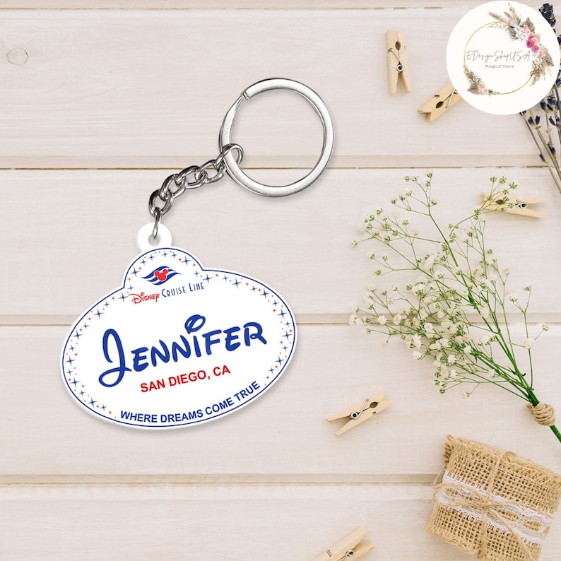 May include: White oval-shaped keychain with a blue and red Disney Cruise Line logo, the text "JENNIFER", "SAN DIEGO, CA", and "WHERE DREAMS COME TRUE".