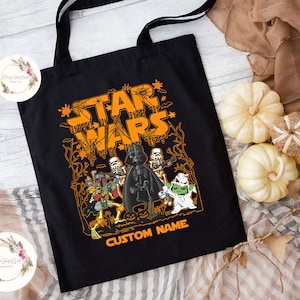 May include: Black tote bag with a Halloween-themed Star Wars design. The design features a dripping orange "Star Wars" text with skeletons, Darth Vader, and a Yoda character. The text "CUSTOM NAME" is at the bottom of the bag.