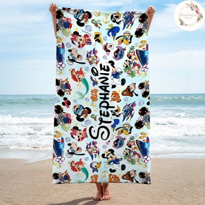 Puede incluir: Una toalla de playa azul con un patr&oacute;n colorido de personajes de Disney, incluyendo Mickey Mouse, Minnie Mouse, Stitch, Ariel y Donald Duck. La toalla tiene el nombre "STEPHANIE" escrito en cursiva negra.