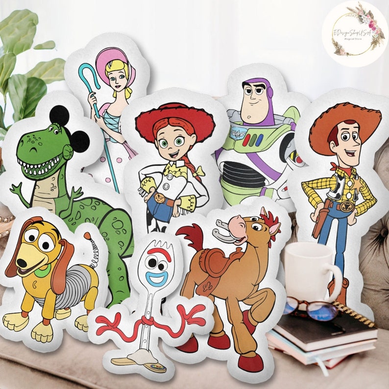 Op de afbeelding: Een set van negen pluche kussens met personages uit de Toy Story-franchise. De personages zijn Woody, Buzz Lightyear, Jessie, Rex, Slinky Dog, Forky, Bullseye, Bo Peep en een groene dinosaurus.