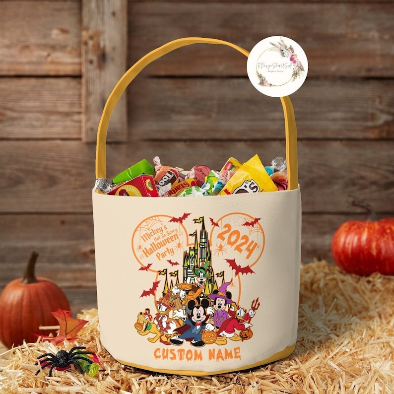 May include: A yellow and white Halloween trick-or-treat bag with Mickey Mouse and friends. The bag features a Mickey Mouse ear design, a castle, and the text "Mickey's Not-So-Scary Halloween Party 2024".
