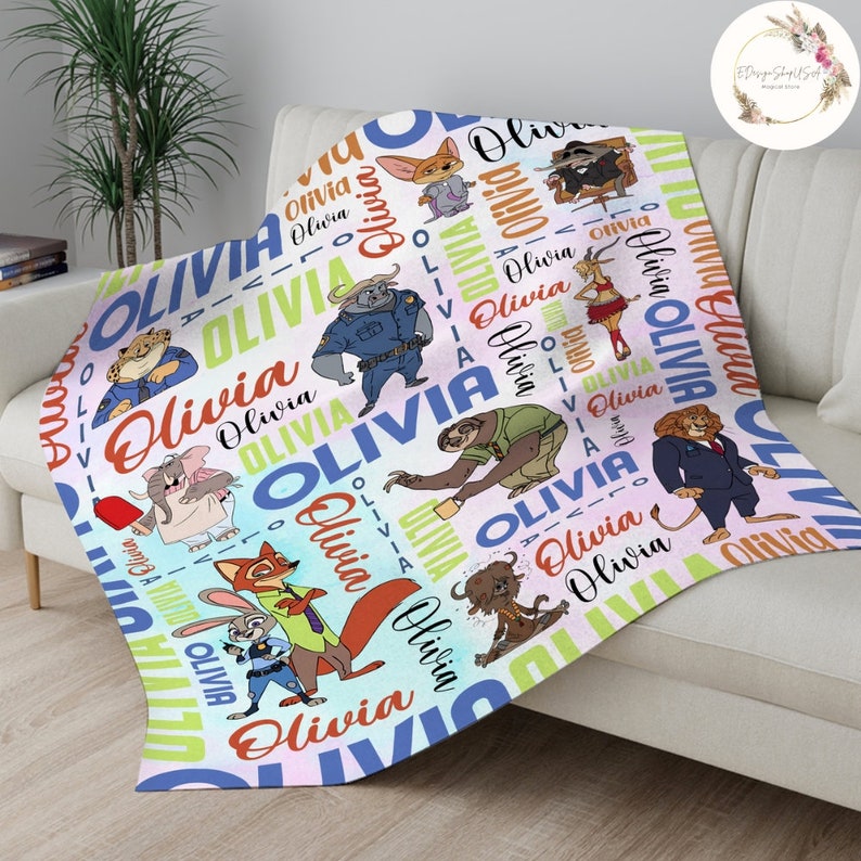 Pu&ograve; includere: Una coperta in pile colorata con un motivo ripetitivo di animali dei cartoni animati e il nome "Olivia" in vari caratteri e colori. Gli animali includono un bradipo, una volpe, un leone, un ghepardo e un poliziotto.