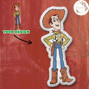 Op de afbeelding: Een witte en bruine vilt applique van Woody uit Toy Story. Woody draagt een geel en bruin vest, een blauwe spijkerbroek en bruine cowboylaarzen. Hij heeft een rode bandana om zijn nek en een sheriffster op zijn vest.