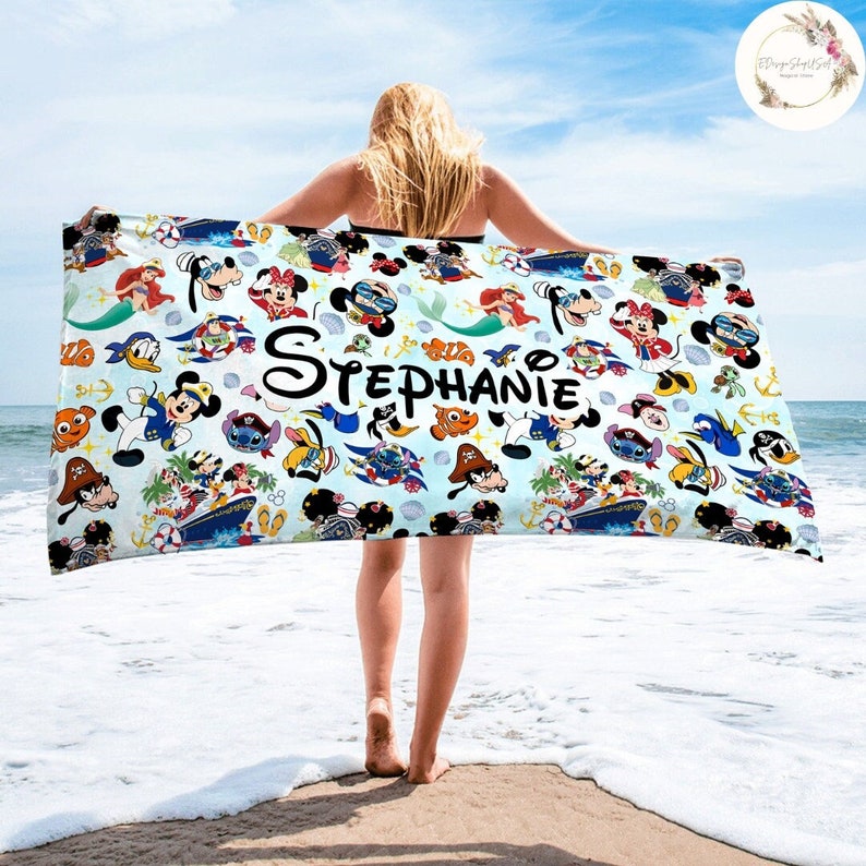 Puede incluir: Una toalla de playa azul con un patr&oacute;n colorido de personajes de Disney, incluyendo Mickey Mouse, Minnie Mouse, Donald Duck, Goofy y Stitch. La toalla tiene el nombre "Stephanie" impreso en ella.