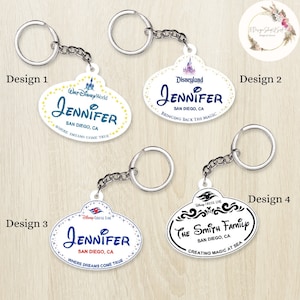 May include: Four different designs for personalized Disney-themed keychains. Each keychain features a white oval-shaped tag with a Disney logo and text. The text includes "Jennifer", "San Diego, CA", and "Where Dreams Come True".