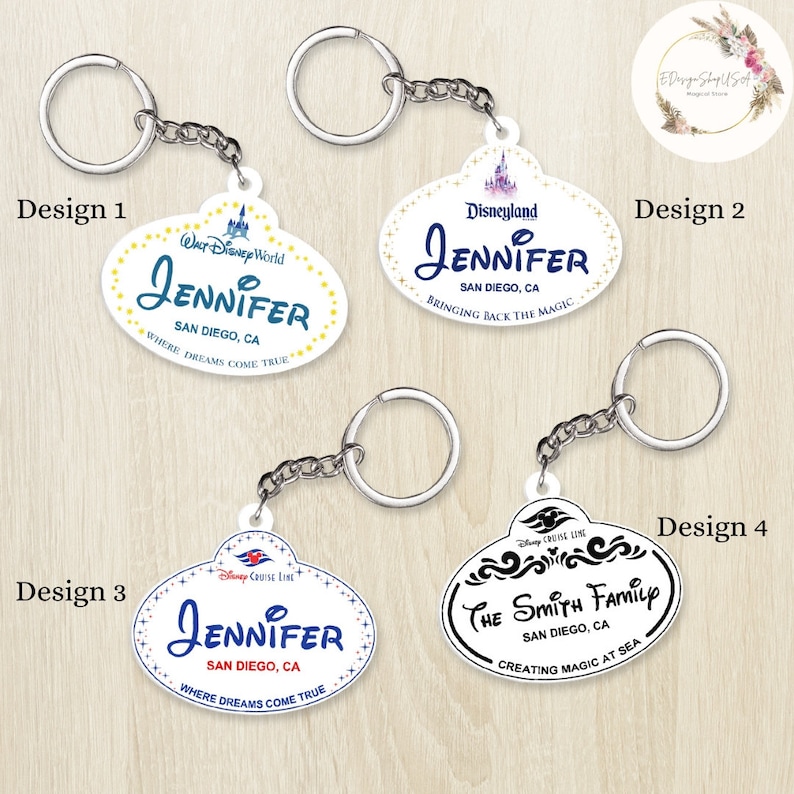May include: Four different designs for personalized Disney-themed keychains. Each keychain features a white oval-shaped tag with a Disney logo and text. The text includes "Jennifer", "San Diego, CA", and "Where Dreams Come True".