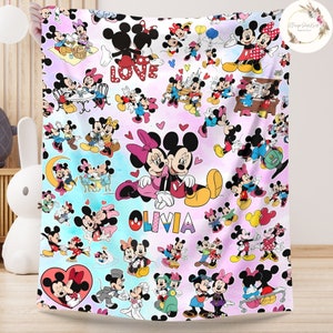 May include: A pink and blue patterned fleece blanket with a repeating pattern of Mickey Mouse and Minnie Mouse characters. The blanket features the word "LOVE" and the name "OLIVIA" in a colourful font.