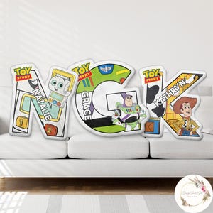 May include: Custom Toy Story themed pillows spelling out the letters N, G, and K. Each letter features a different character: Natalie, Grace, and Kathryn. The pillows are white with colorful character designs.
